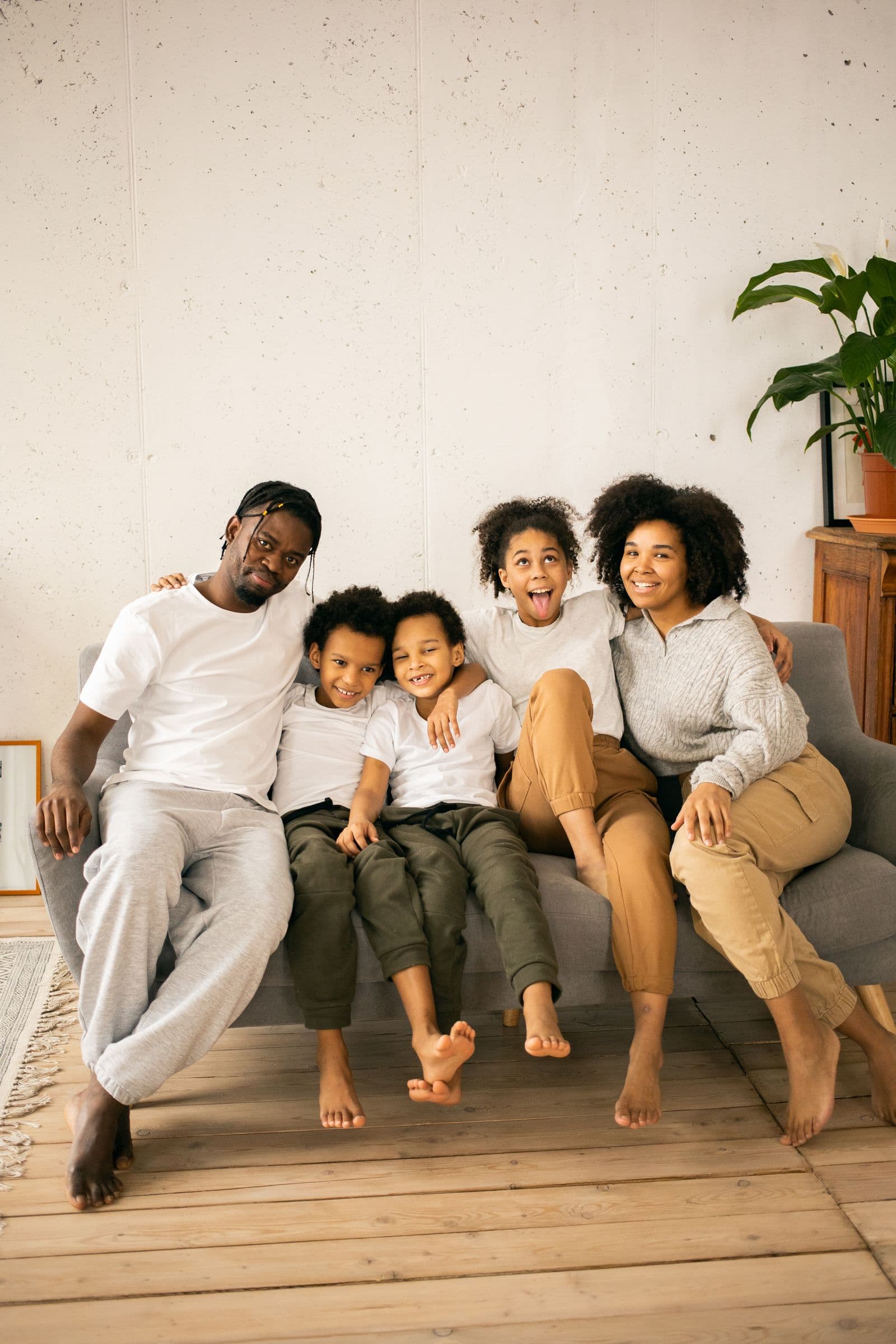 A family of five sitting together on a couch at home