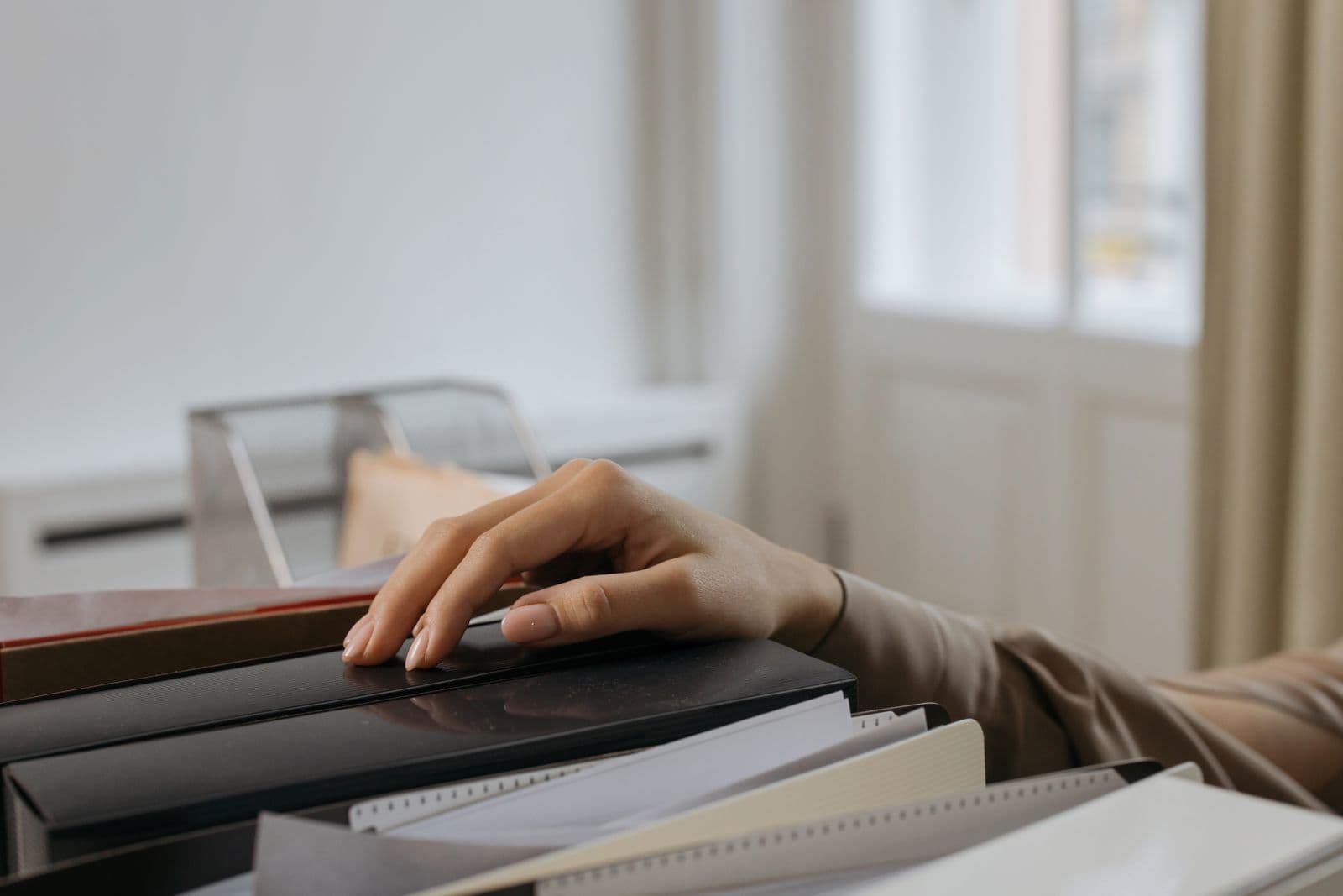 A hand resting on a stack of file folders and records